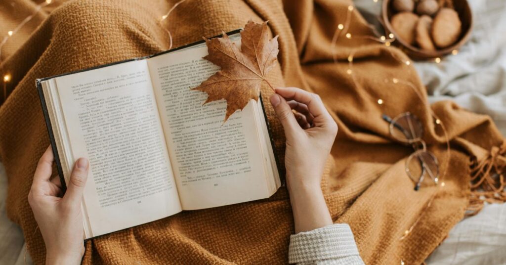Open book with autumn leaf and soft lights, capturing the quiet mood of The Secret History by Donna Tartt.